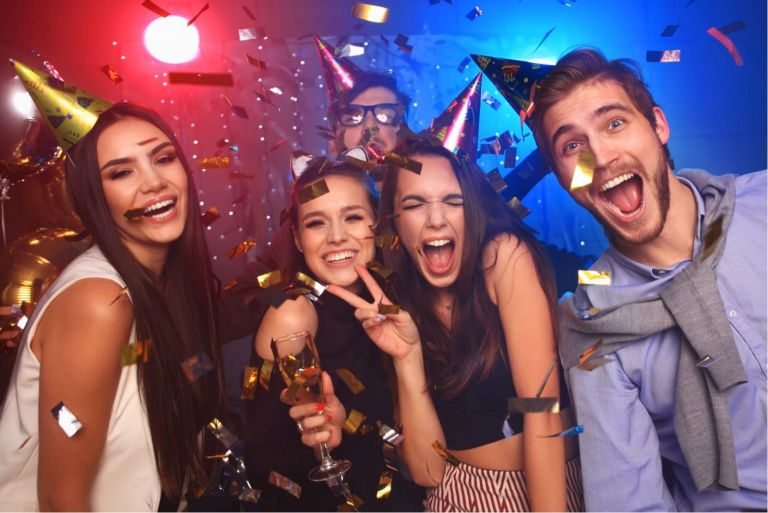 Quattro persone che lanciano coriandoli e bevono champagne