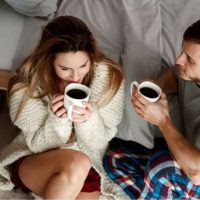 pareja hablando con café al lado de la cama sentada en el suelo