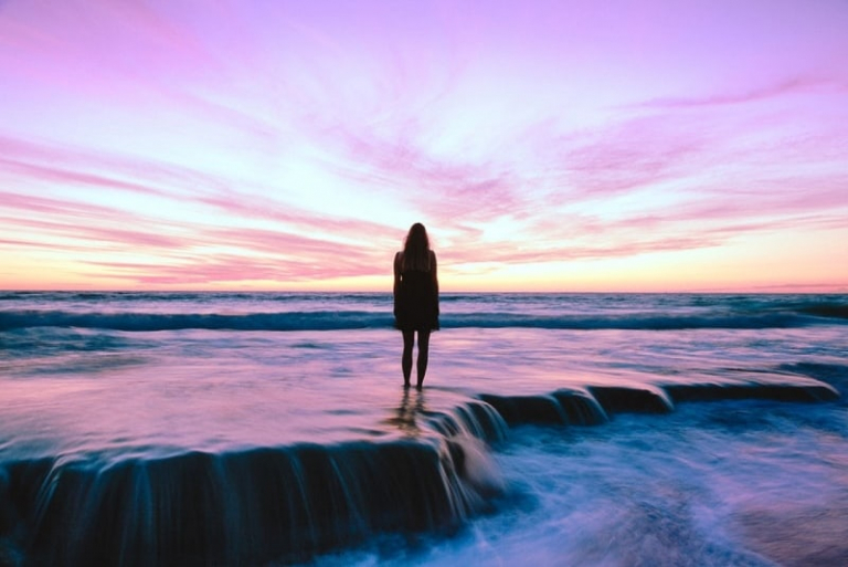 woman standing on seashore during golden hour