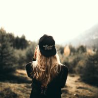 donna con cappello nero in piedi nella foresta