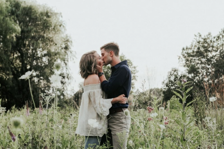 man and woman kissing on grass field
