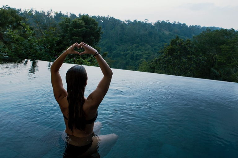 woman in infinity pool making heart hand gesture