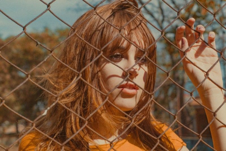 woman in yellow top leaning on fence