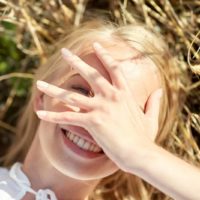 a portrait of a young woman lying in the grass while on vacation