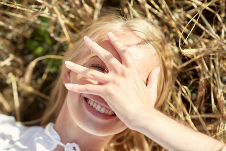 a portrait of a young woman lying in the grass while on vacation