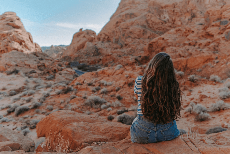 woman in denim shorts sitting on rock
