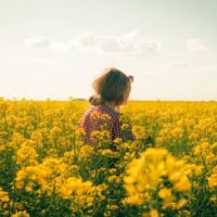 mulher de pé num campo de flores amarelas