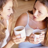 women talking with coffee wearing white tank tops