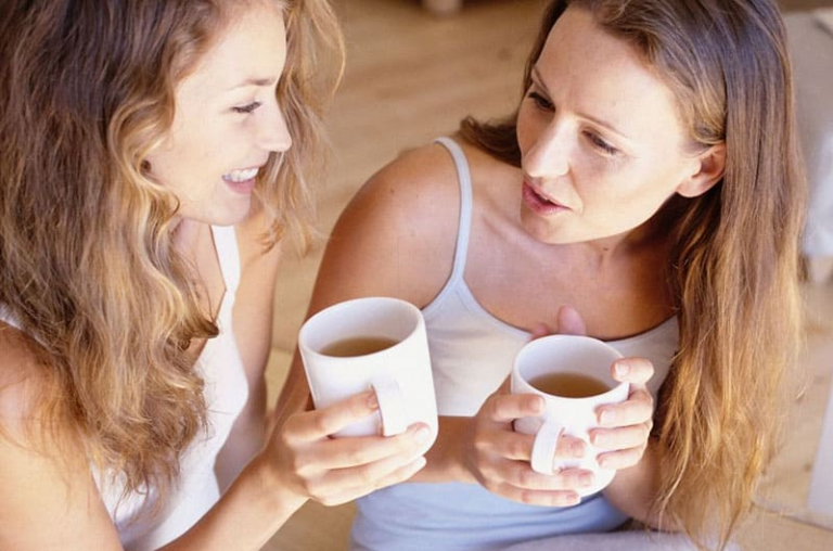 women talking with coffee wearing white tank tops