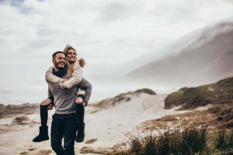 man piggybacking smiling woman outdoors