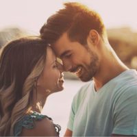 sweet couple with face close to each other near a body of of water