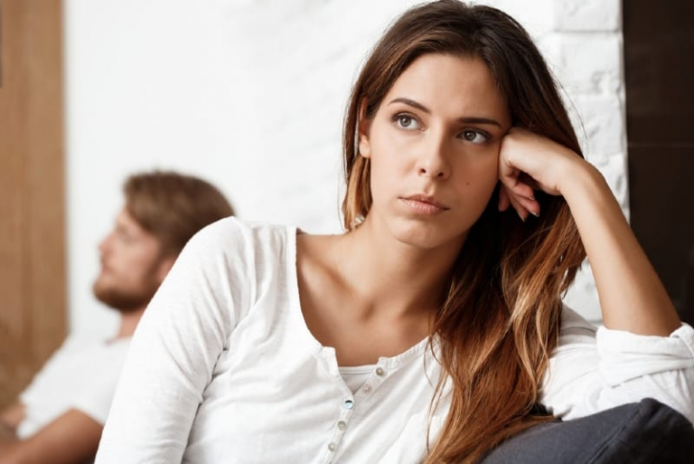 sad woman in white shirt leaning on sofa