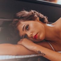 woman with red lipstick leaning on piano