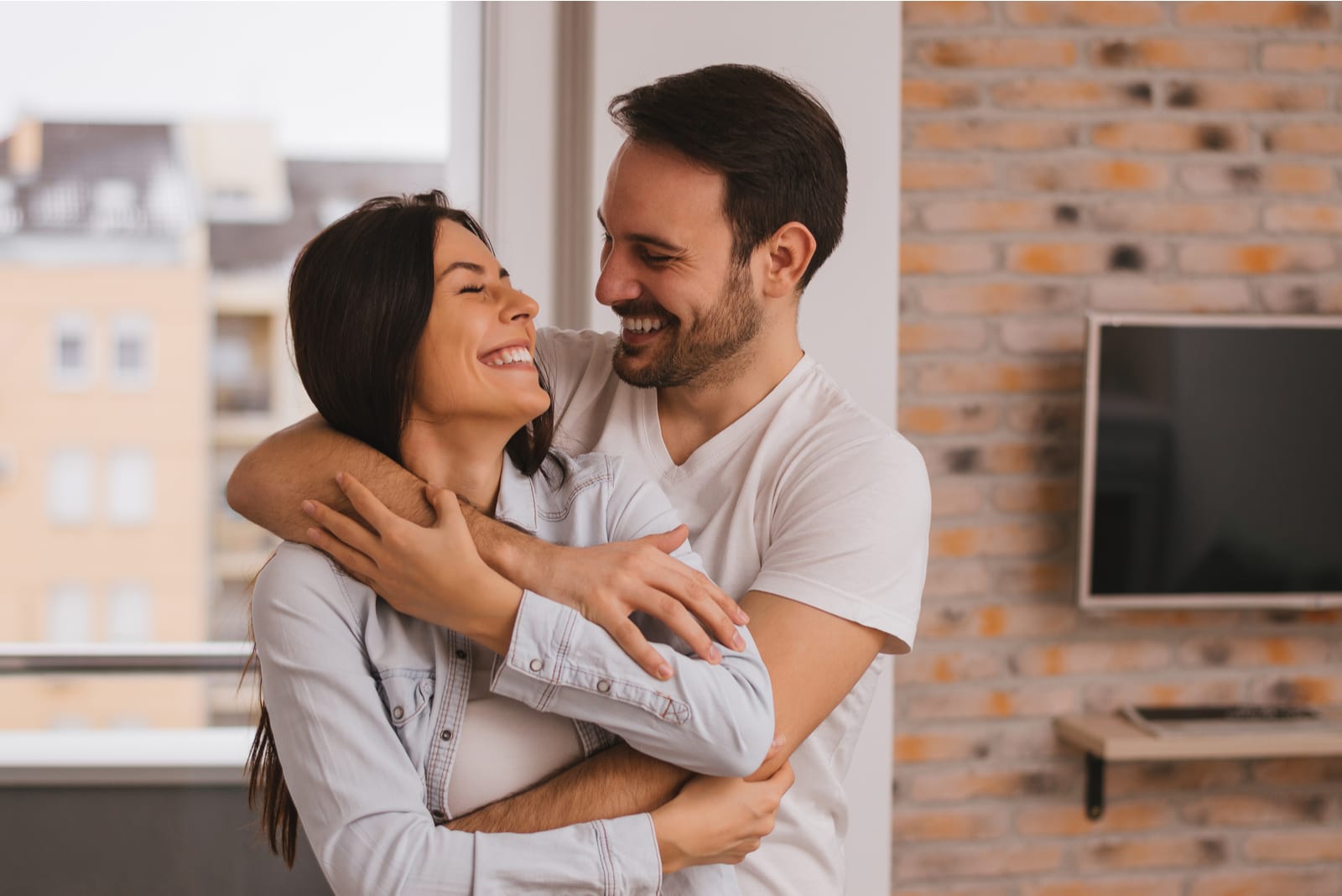 una pareja feliz abrazándose y mirándose en la casa