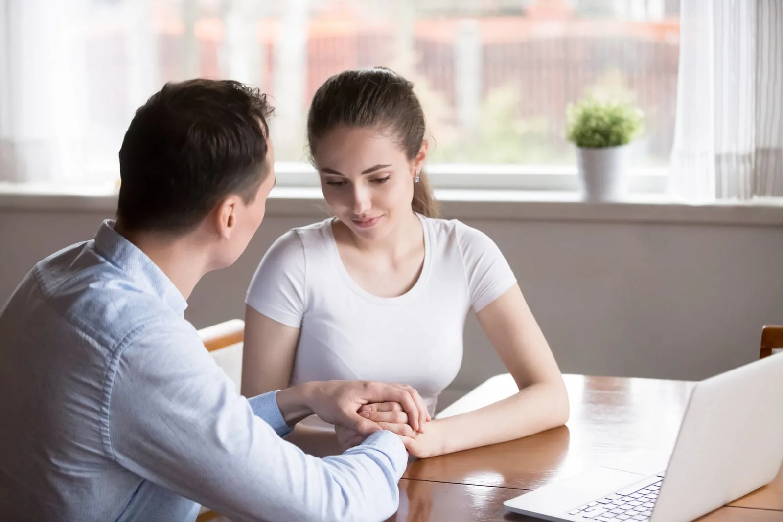 a loving couple sitting at a table holding hands and talking