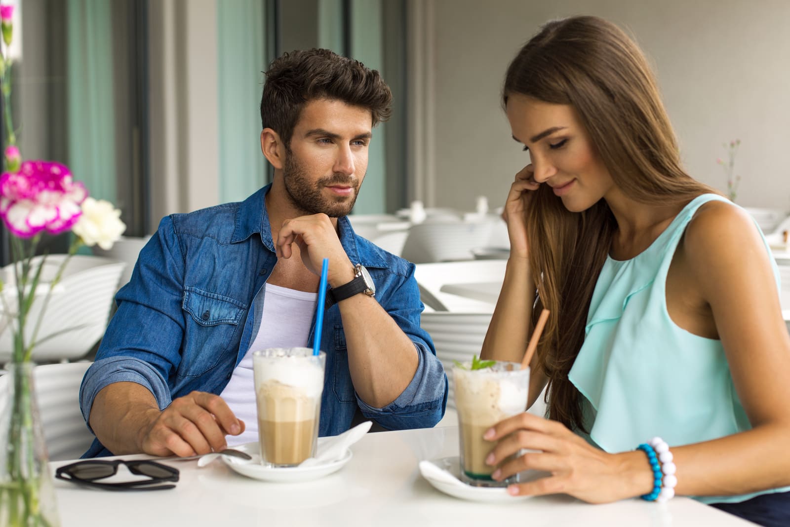 a man and a woman are sitting drinking hot chocolate.