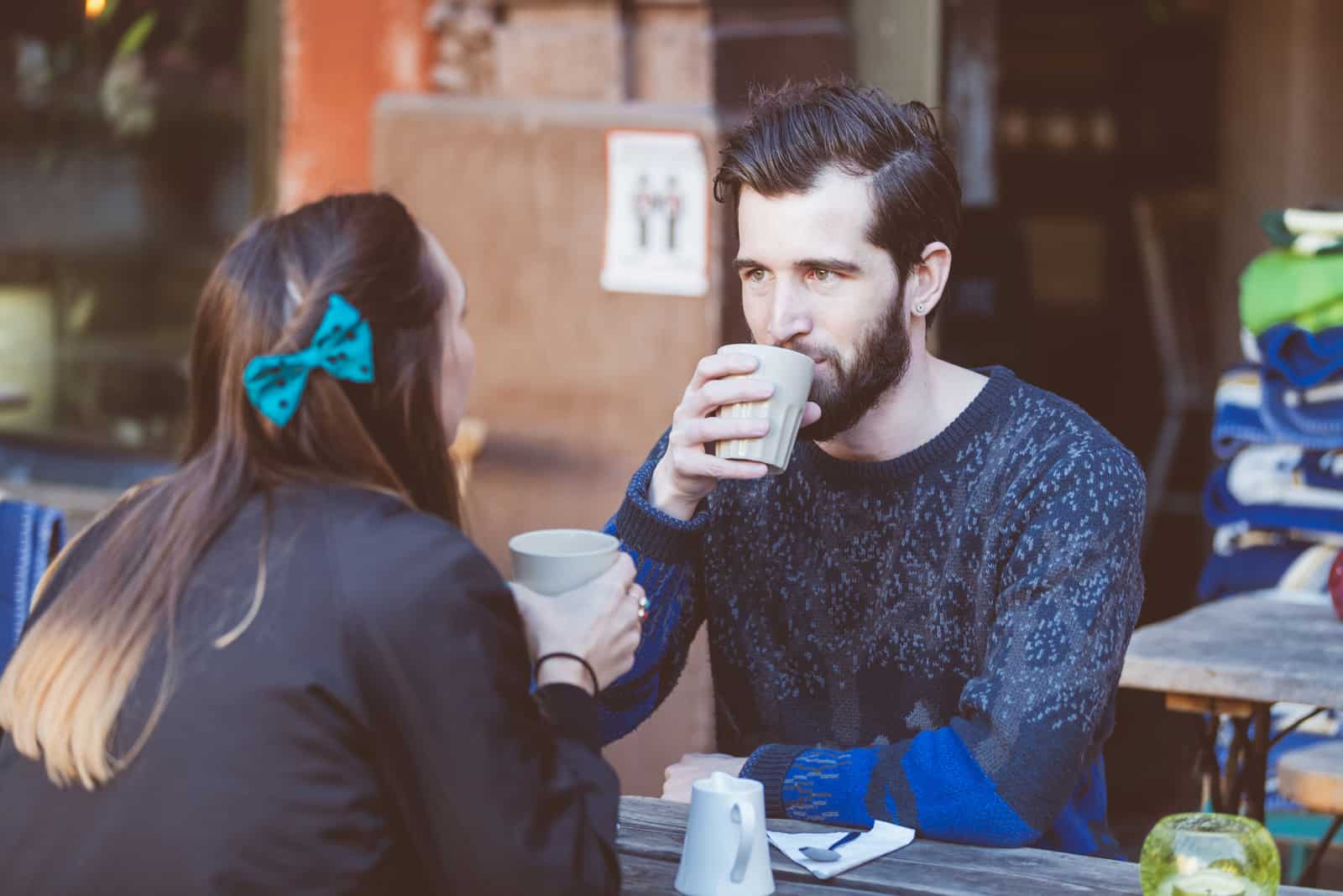 a man and a woman drinking coffee at the table