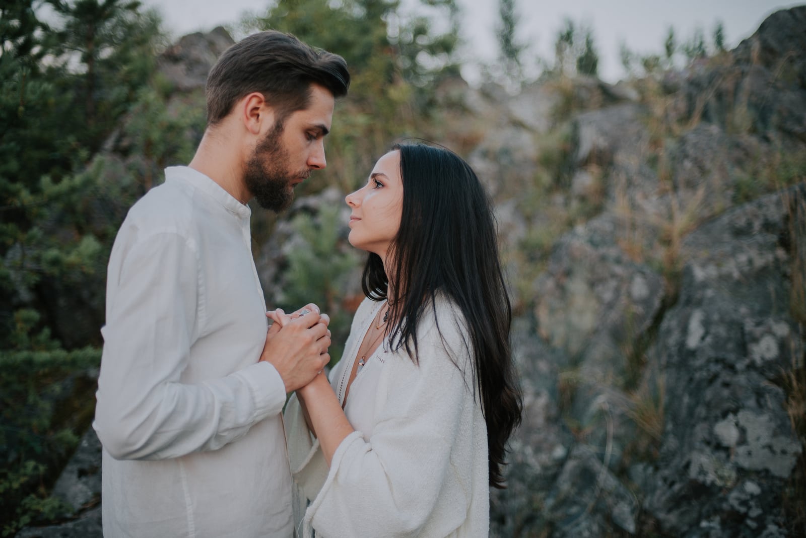 a sad loving couple standing in nature holding hands and looking at each other