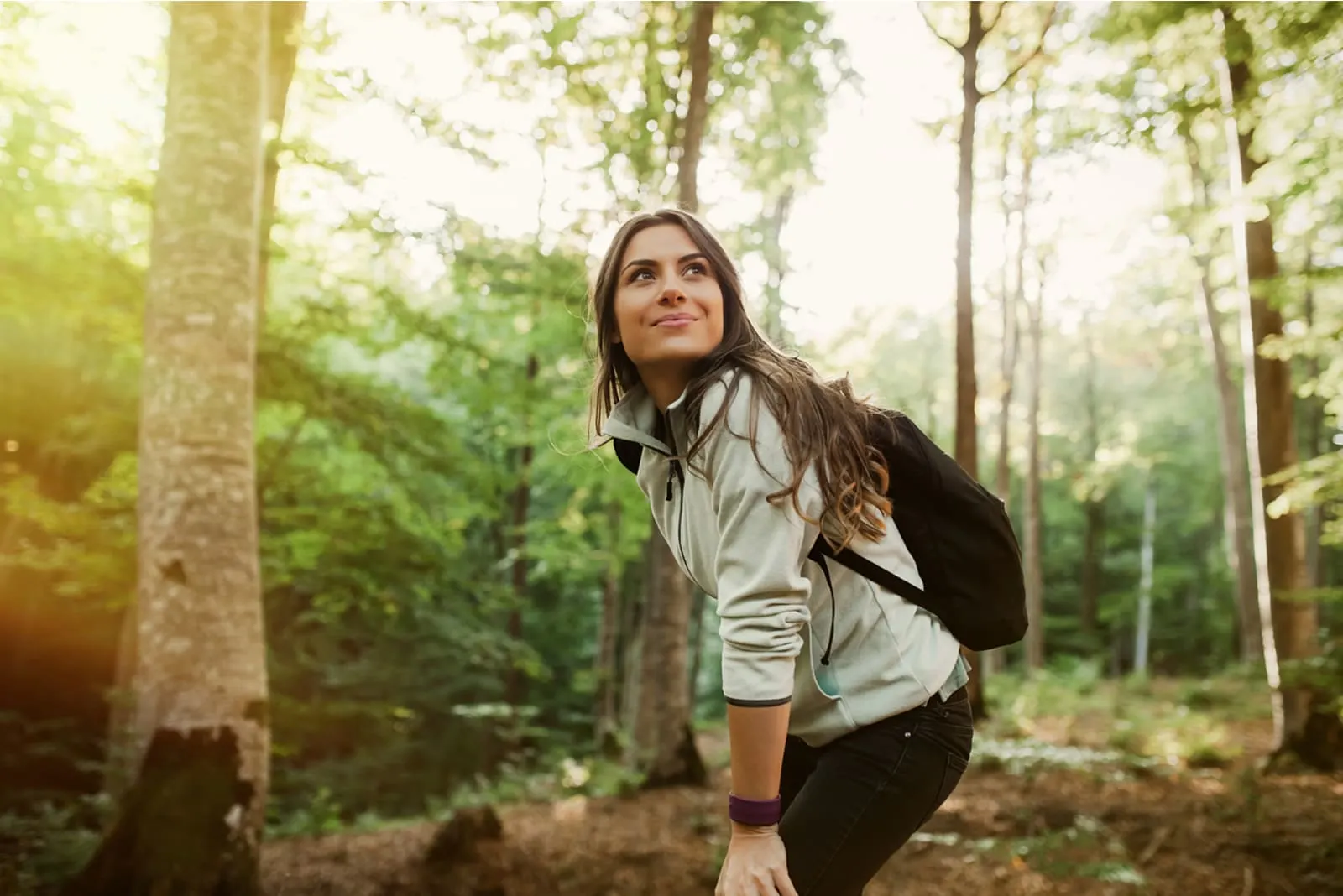 a smiling girl stands in the woods
