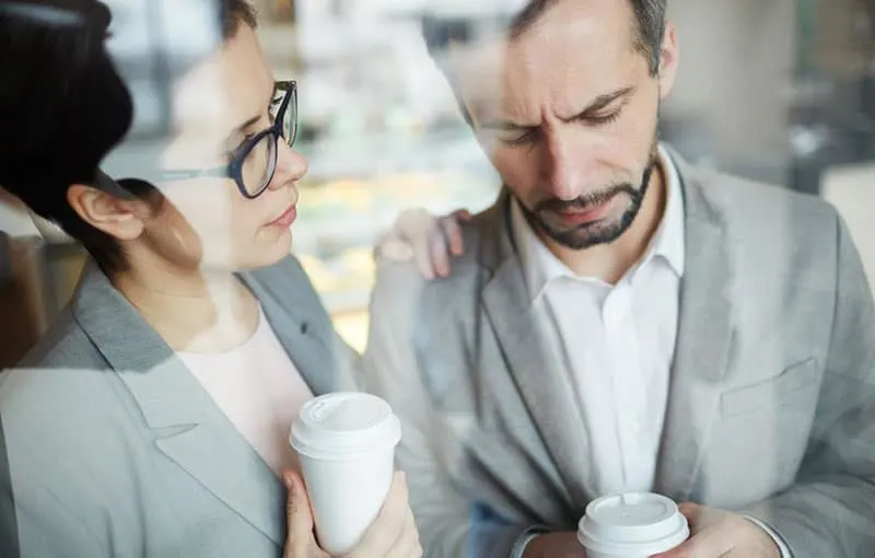 business woman trying to comfort a sad man while on coffee break