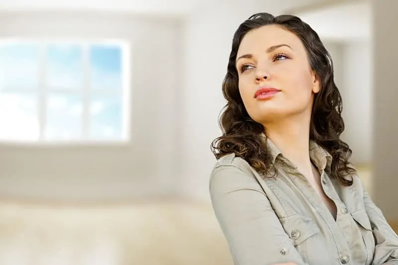 confident woman in gray top inside an empty room