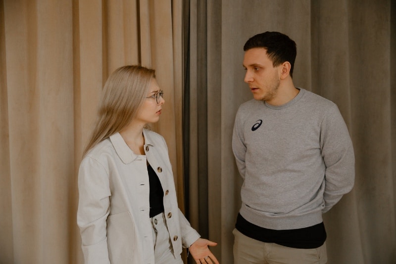 woman in white jacket and man arguing indoor