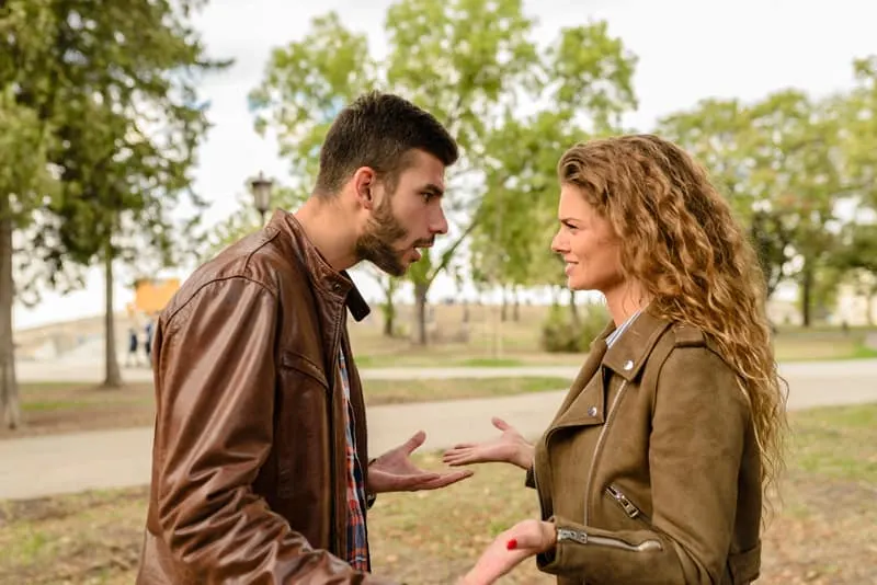 couple fighting in the park wearing brown leather jackets
