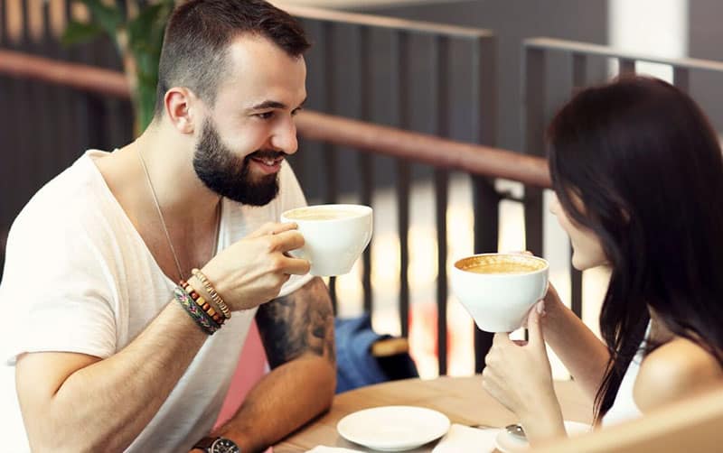 coppia in pausa caffè seduta accanto alla ringhiera del bar