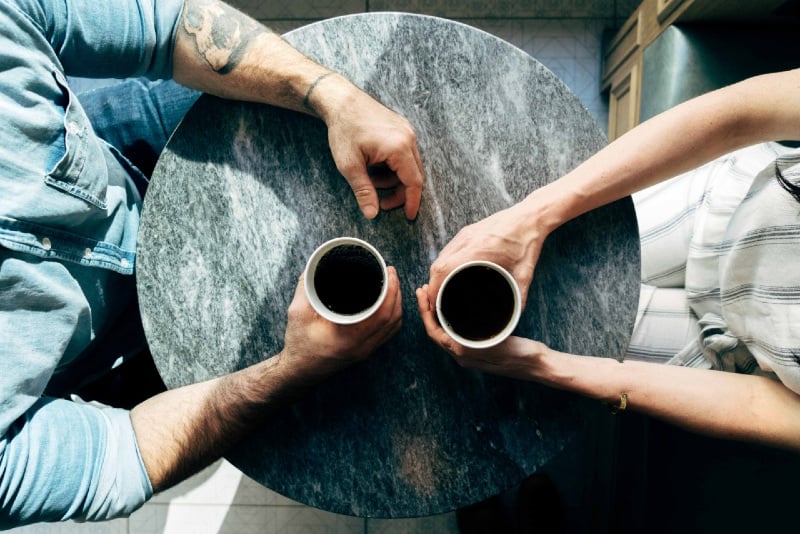 hombre y mujer sosteniendo tazas de café en una cafetería