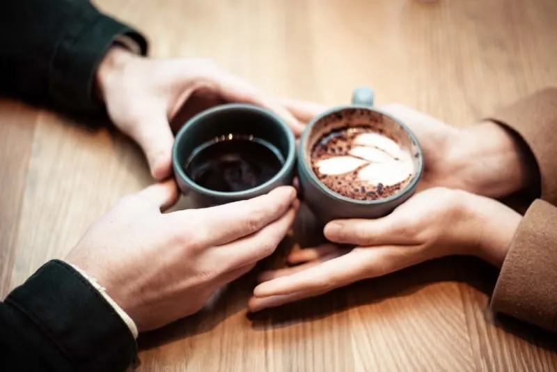 man and woman holding ceramic mugs with coffee