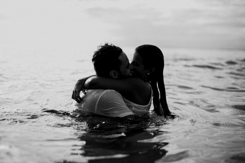 man and woman kissing in water