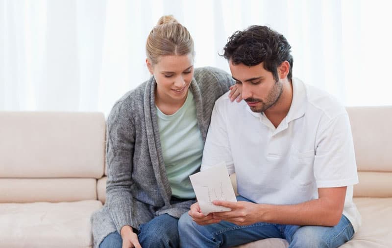 couple looking at an envelope while sitting on a sofa