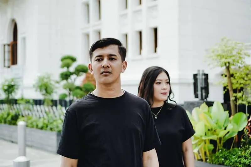couple looking at different direction standing outdoors wearing black shirts