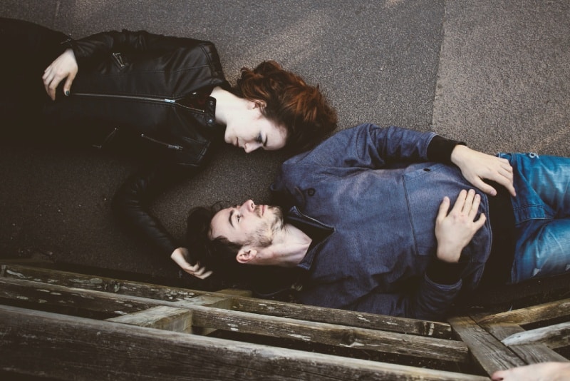 woman and man making eye contact while lying on concrete