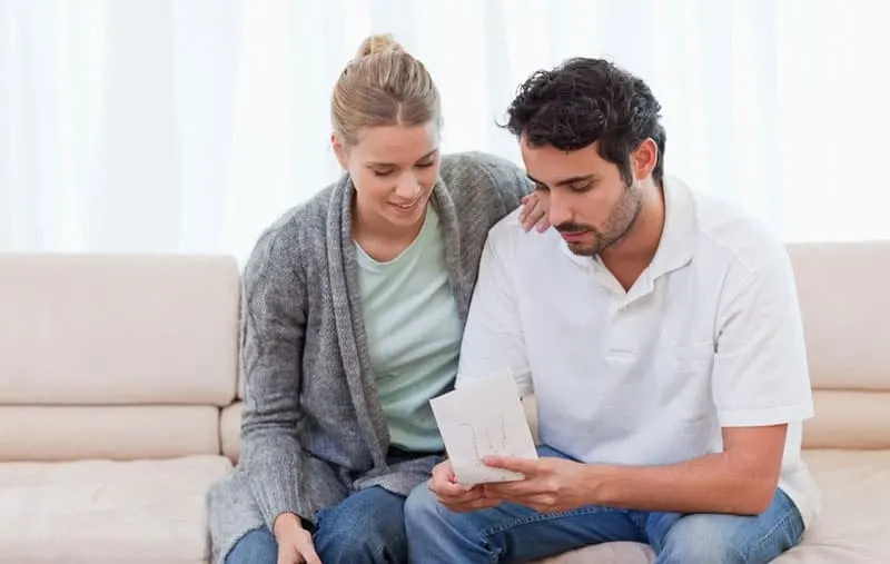 couple opening up an envelope in their living room