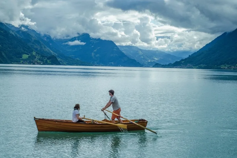 man and woman riding boat near mountain