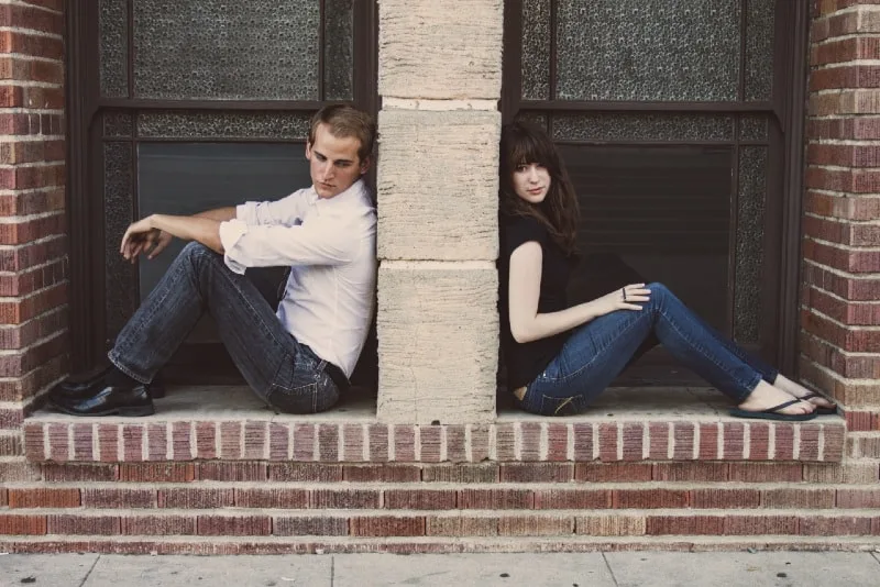 man and woman sitting on floor while leaning on wall