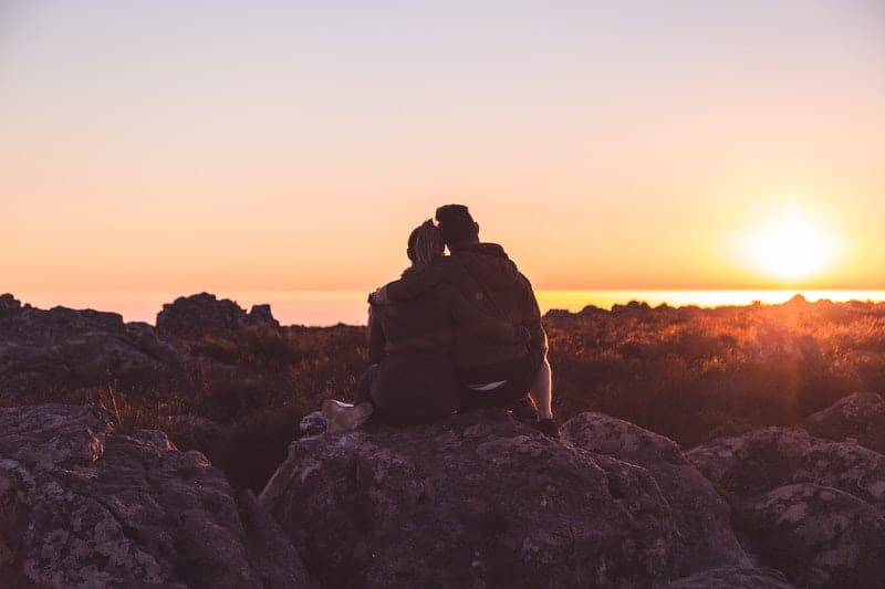 couple sitting on rocks while watching the sunrise/sunset