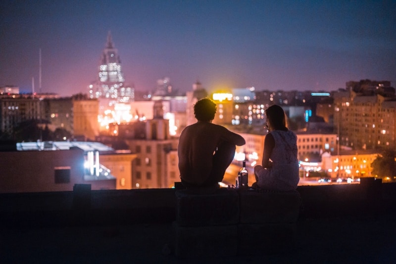 man and woman sitting in front of high-rise buildings