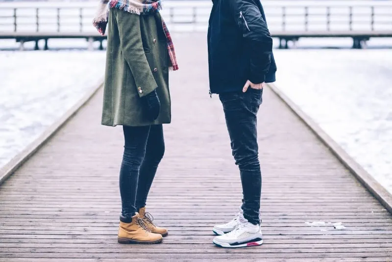 woman and man standing on brown wooden dock
