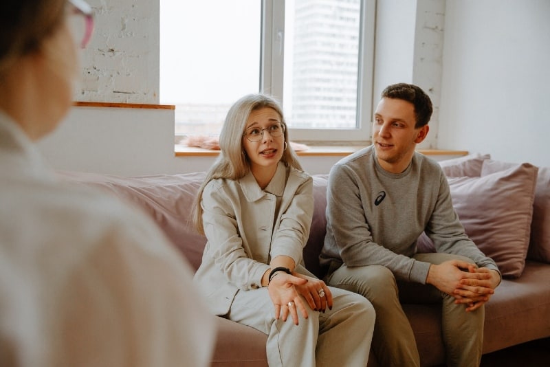 man and woman talking to therapist while sitting on couch