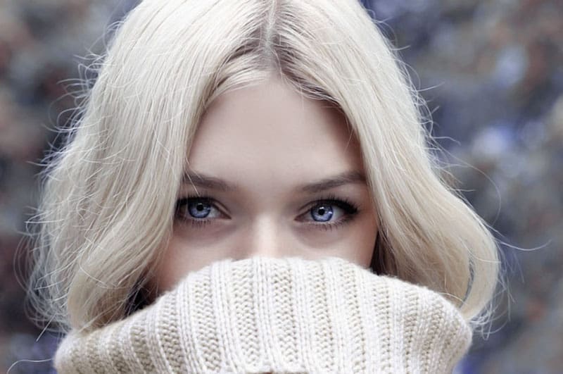 focused photo of a woman's face covered with her turtle neck sweater