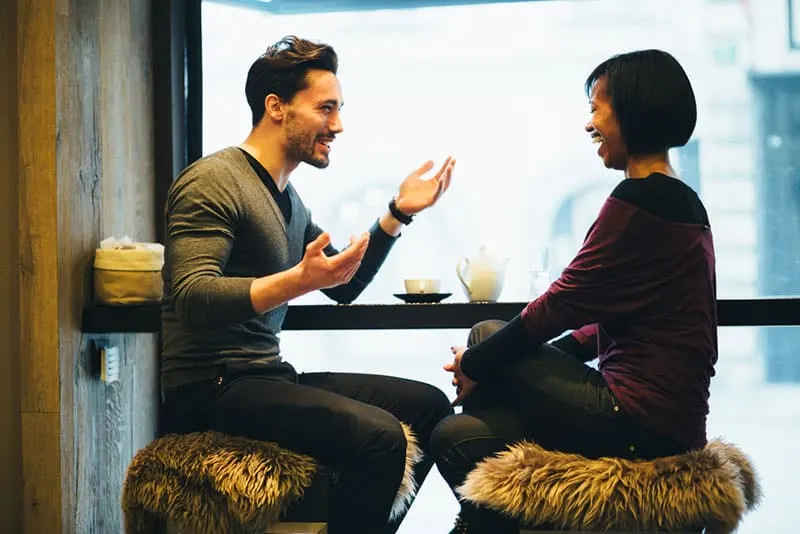 happy man talking to smiling woman at cafe