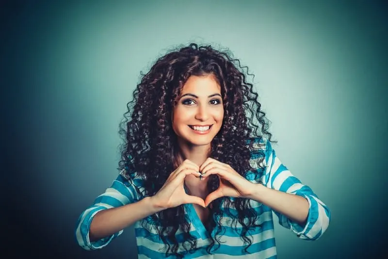Happy brunette woman making heart shape with hands
