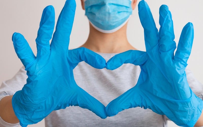 Forma di cuore con mani di infermiera coperte da guanti chirurgici blu