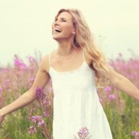 Mulher feliz de vestido branco num campo com flores