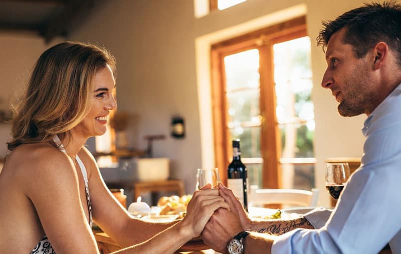 loving young couple holding hands at dining table