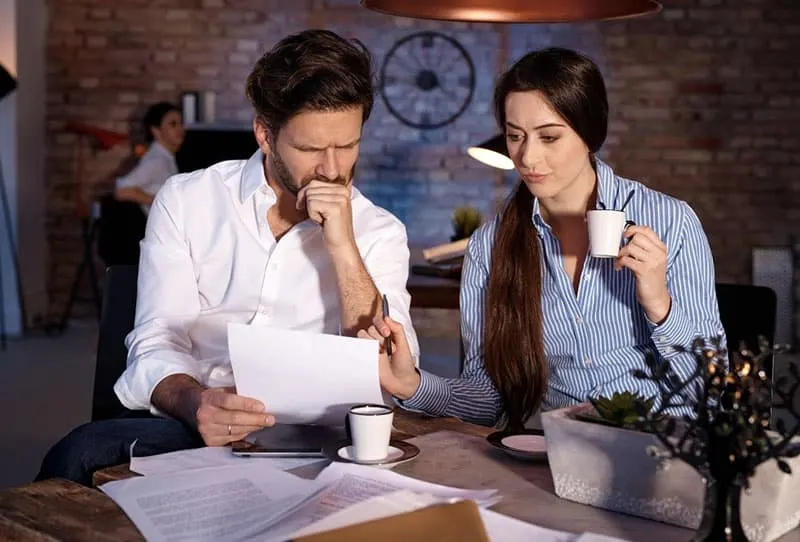 man and woman discussing over papers while having coffee in a cafe during nightime