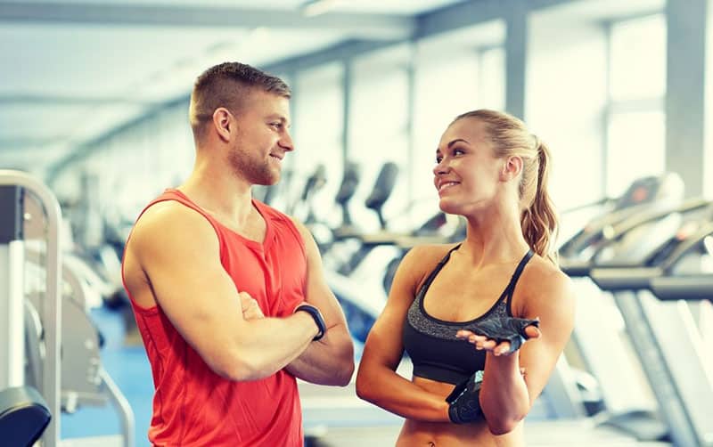 hombre y mujer en el gimnasio hablando en traje de gimnasia