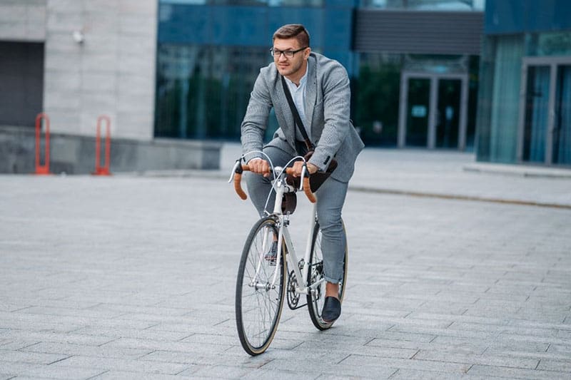 uomo che va in bicicletta al lavoro indossando un abbigliamento da ufficio